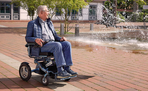 Älterer Mann nutzt einen faltbaren MovingStar-Elektrorollstuhl auf einem Platz