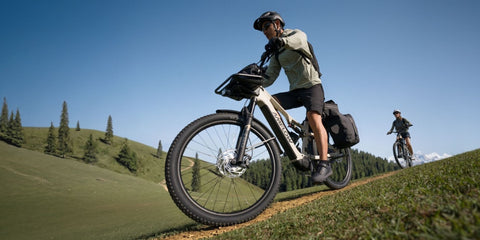 Fahrerin mit Helm auf einem Amflow TL Carbon mit Gepäcktaschen auf einem unbefestigten Weg